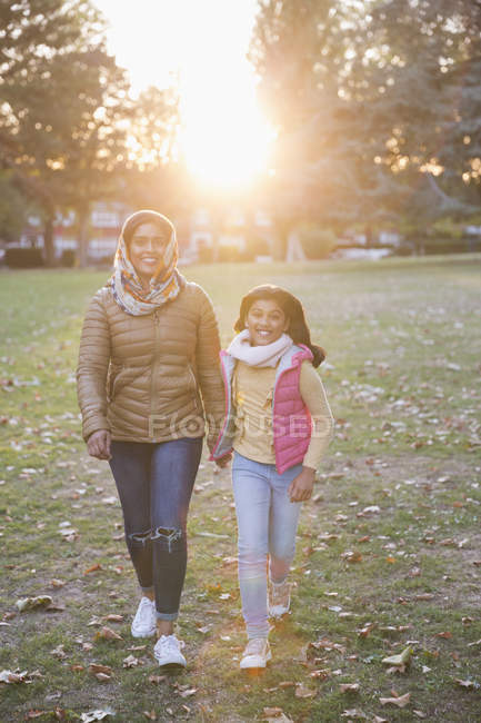 Retrato mãe muçulmana feliz e filha andando no ensolarado parque de outono — Fotografia de Stock