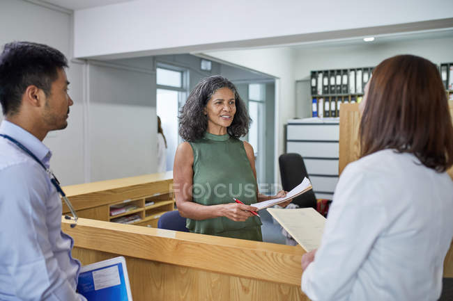 Médicos y recepcionistas hablando en clínica - foto de stock