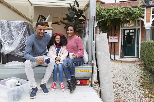 Retrato feliz família beber chá na parte de trás da van em movimento fora nova casa — Fotografia de Stock