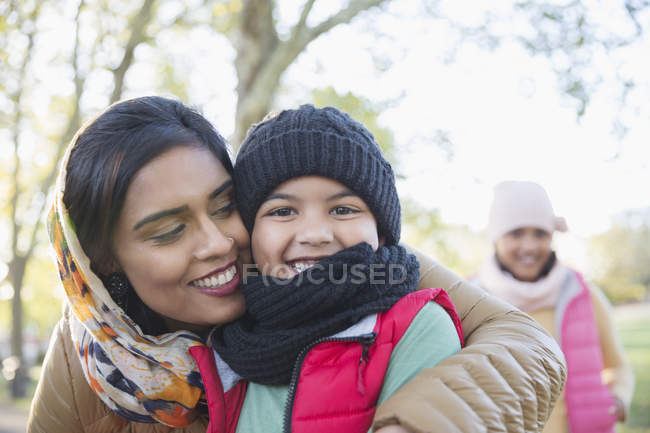 Portrait happy Muslim mother in hijab hugging son in autumn park — Stock Photo