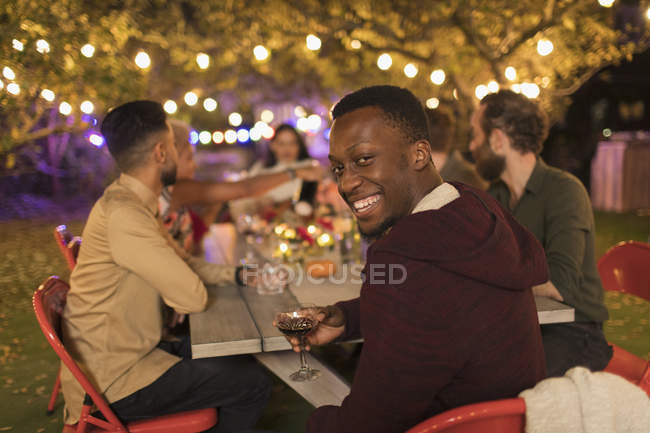 Retrato sorrindo homem bebendo vinho, desfrutando de jantar jardim festa — Fotografia de Stock