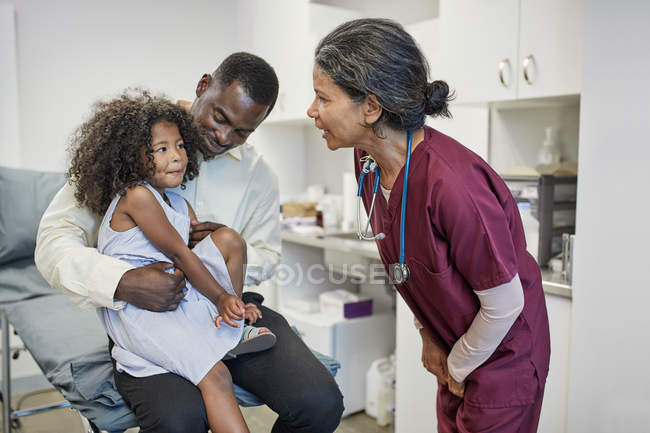 Pediatra hablando con el padre y la hija en la sala de examen clínico - foto de stock