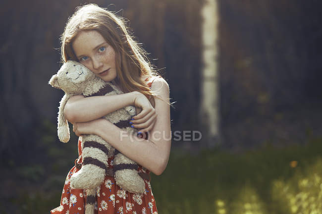 Милая девушка на улице, обнимающая старинную игрушку медведя — стоковое фото