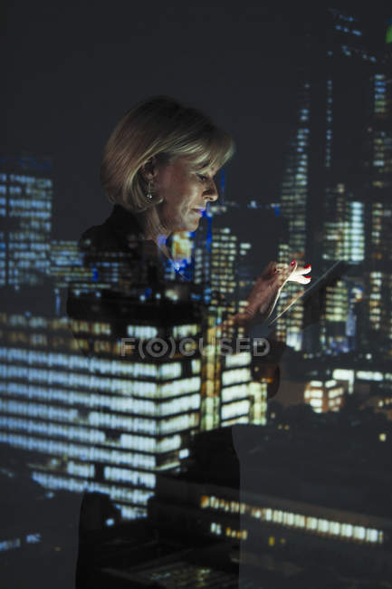 Doble exposición de la mujer de negocios con smartphone contra las luces de rascacielos en la noche - foto de stock
