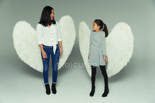 Happy mother and daughter wearing angel wings — Stock Photo