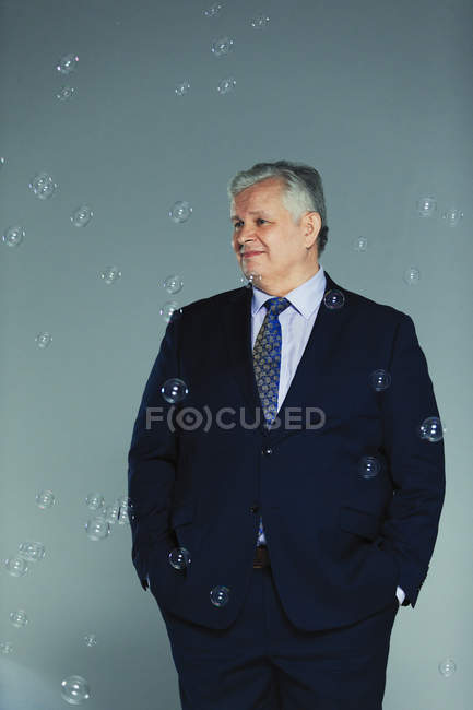 Burbujas cayendo alrededor sonriente hombre de negocios - foto de stock