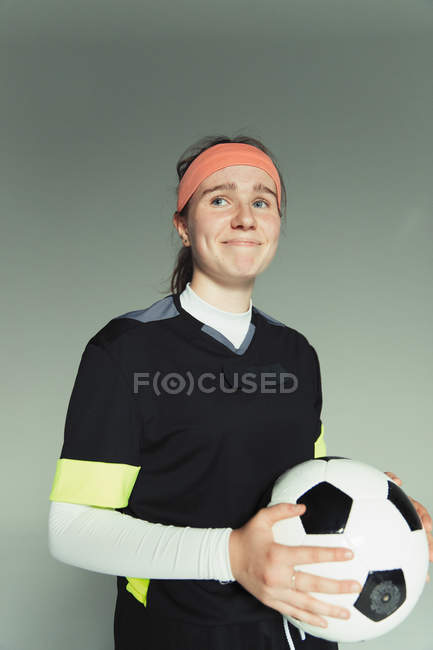 Retrato de sonriente, confiado jugador de fútbol adolescente sosteniendo la pelota - foto de stock