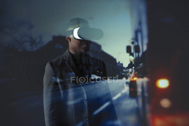 Double exposure businessman with virtual reality simulator glasses against city street — Stock Photo