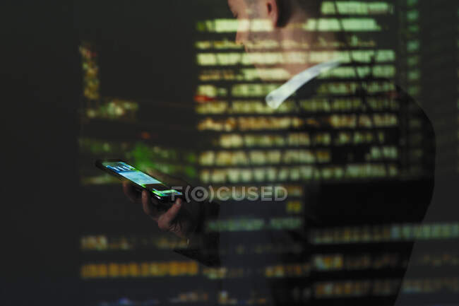 Doble exposición hombre de negocios utilizando el teléfono inteligente contra rascacielos en la noche - foto de stock