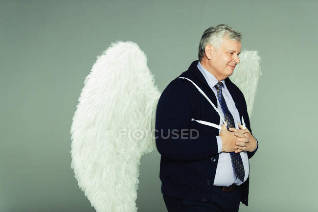 Smiling businessman wearing angel wings — Stock Photo