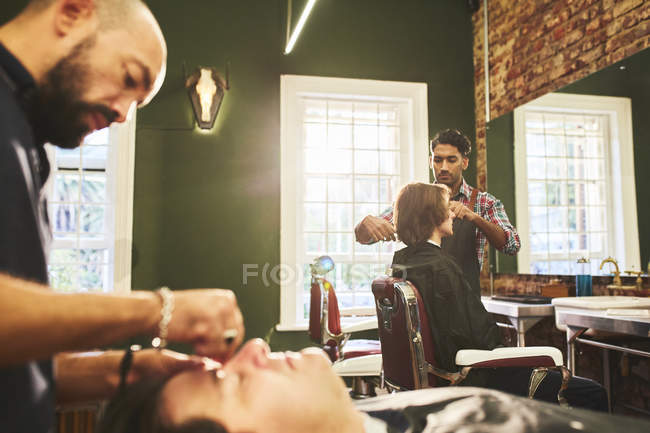 Peluqueros machos trabajando en peluquería - foto de stock