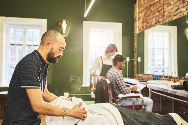 Männliche Friseur dampfenden Gesicht der Kundin in Friseurladen — Stockfoto