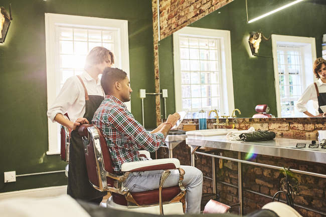 Friseur und Kunde mit digitalem Tablet im Gespräch im Friseurladen — Stockfoto