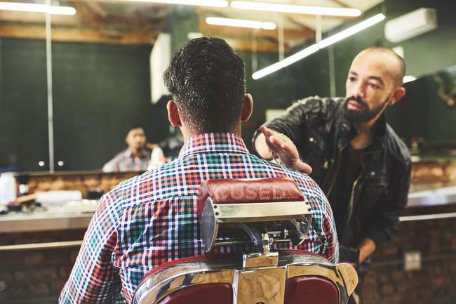 Barbeiro masculino verificando corte de cabelo do cliente na barbearia — Fotografia de Stock