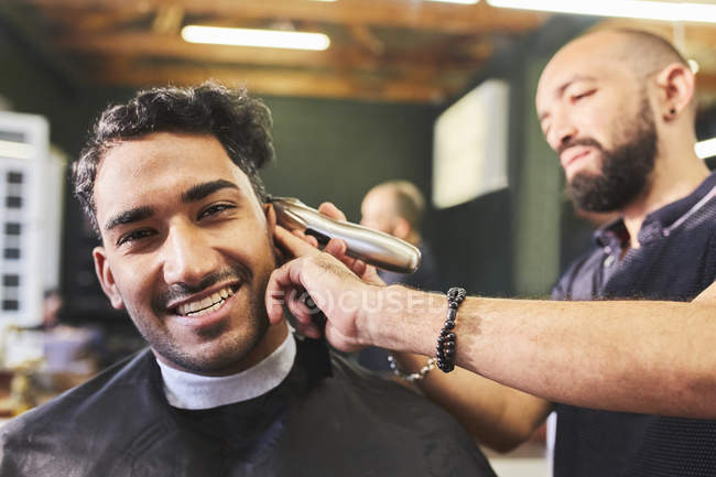 Retrato sorrindo jovem recebendo corte de cabelo na barbearia — Fotografia de Stock