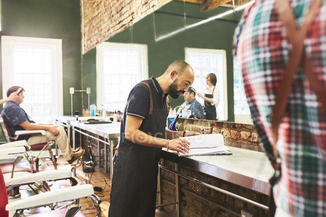 Männlicher Friseur schaut sich Zeitplan im Friseursalon an — Stockfoto