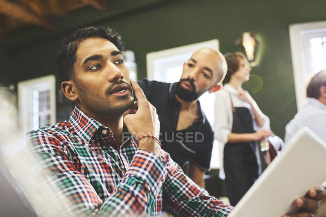 Cliente masculino e barbeiro conversando na barbearia — Fotografia de Stock
