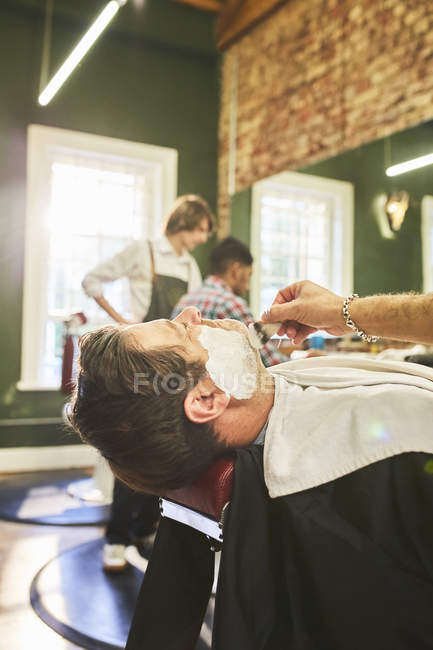 Uomo che riceve una rasatura in barbiere — Foto stock