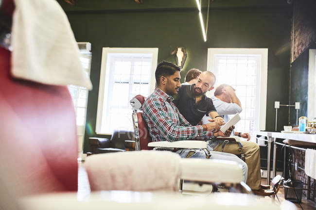 Homme coiffeur et client avec tablette numérique parler dans le salon de coiffure — Photo de stock