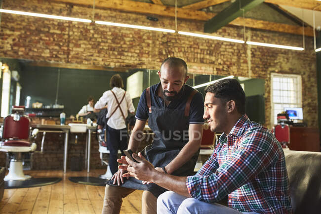Peluquería masculina y cliente con tableta digital en barbería - foto de stock