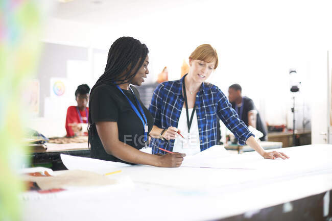 Female fashion designers drawing sewing pattern in studio — Stock Photo