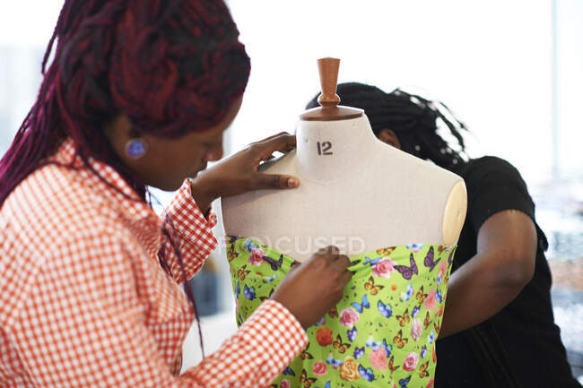 Diseñadores de moda femeninos fijando tela de mariposa en modelo dressmakers - foto de stock
