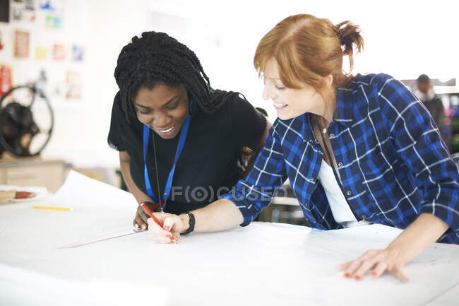 Female fashion designers drawing sewing pattern in studio — Stock Photo