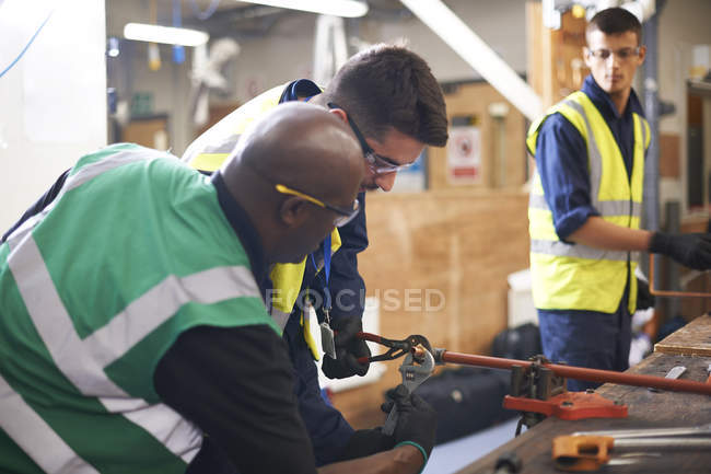 Male instructor helping students in shop class workshop — Stock Photo