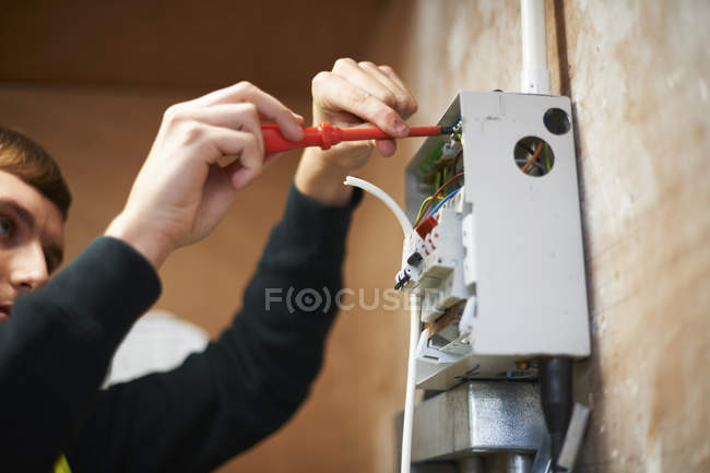 Eletricista masculino usando chave de fenda, trabalhando no painel elétrico — Fotografia de Stock