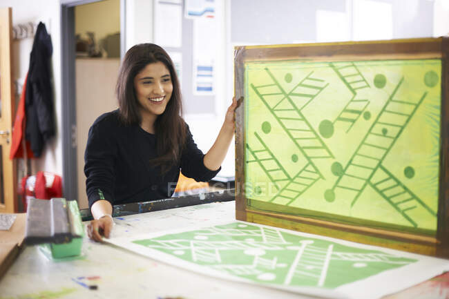Smiling female art student screen printing in art studio — Stock Photo