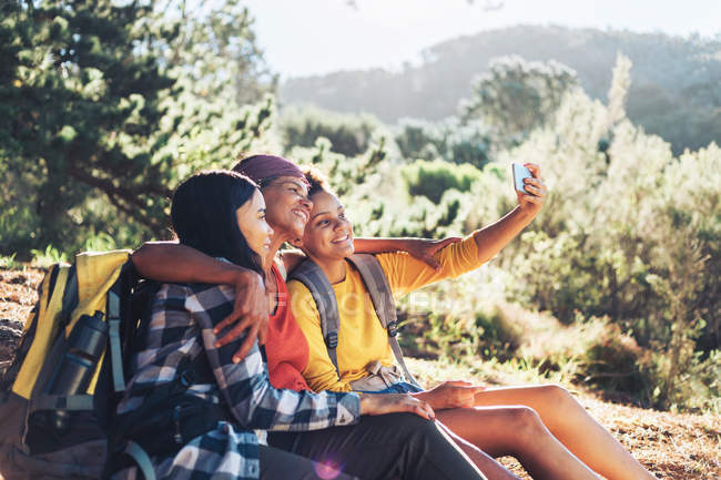 Happy mother and daughters taking selfie, hiking in sunny woods — Stock Photo