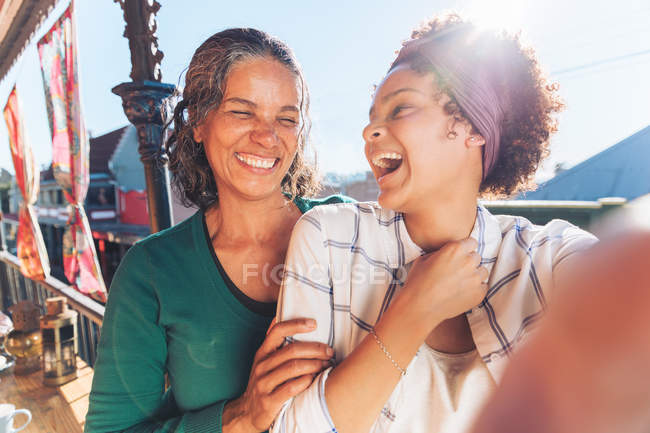 Selfie punto de vista de la risa, feliz madre e hija en el balcón soleado - foto de stock