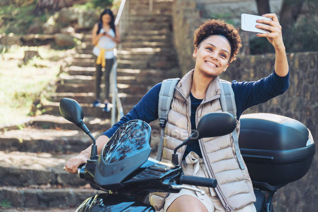 Молода жінка бере селфі з телефоном на мотоциклі — стокове фото
