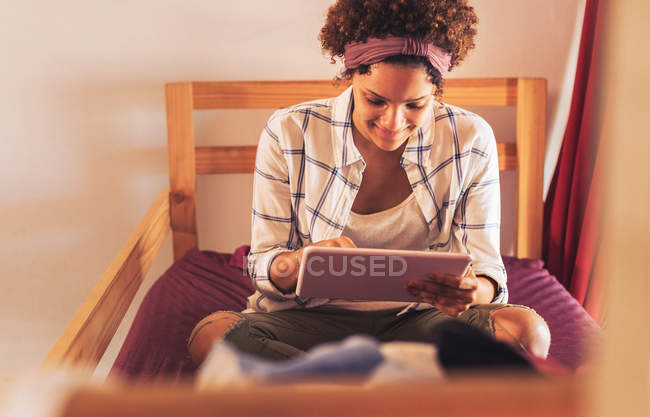 Young female college student using digital tablet on dorm room bunk bed — Stock Photo