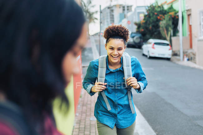 Lachende, glückliche junge Frau mit Rucksack auf Gehweg — Stockfoto