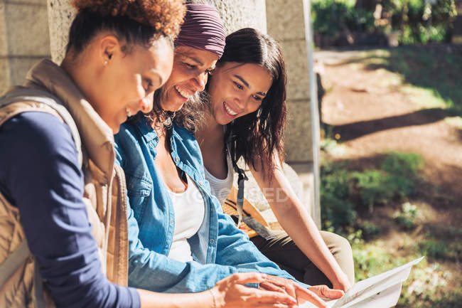 Mother and daughters looking at map in sunny woods — Stock Photo