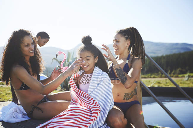 Verspieltes lesbisches Paar legt Sonnencreme auf Tochter am sonnigen, sommerlichen Pool — Stockfoto