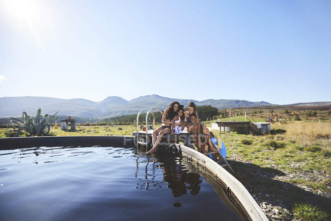 Feliz lésbicas casal e crianças no remoto, ensolarado, verão piscina — Fotografia de Stock