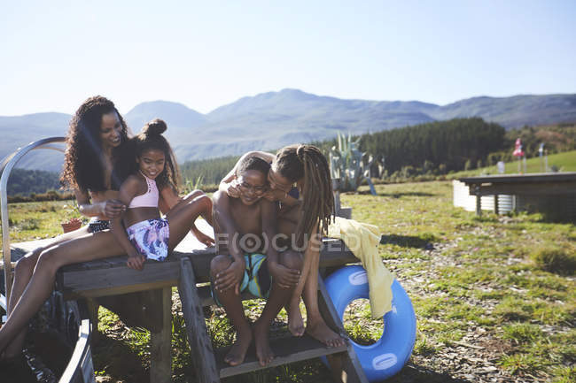 Feliz pareja de lesbianas y niños en soleado, junto a la piscina de verano - foto de stock