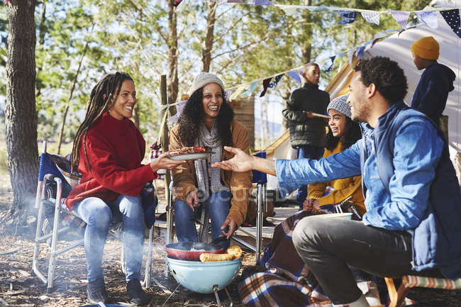 Familia feliz comiendo en el camping soleado - foto de stock