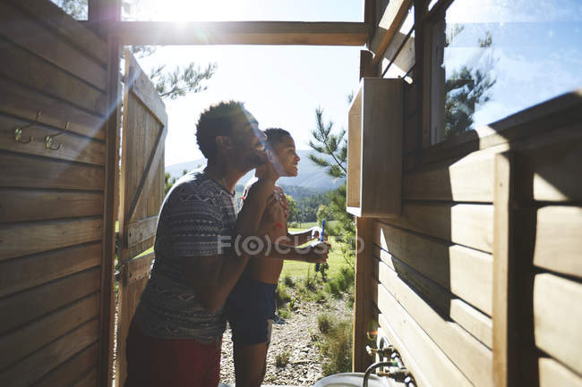 Father and son brushing teeth at sunny campsite bathroom sink — Stock Photo