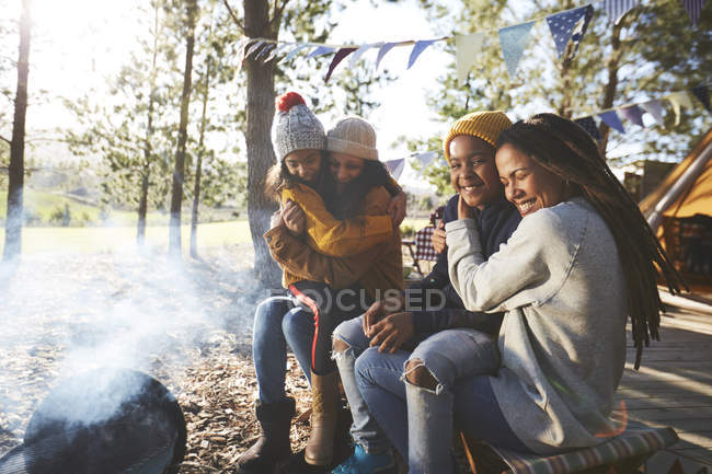 Happy, affectionate lesbian couple hugging kids at campsite — Stock Photo
