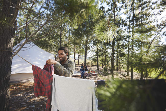 Man hanging laundry on clothesline at campsite in woods — Stock Photo