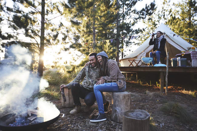 Casal feliz sentado no acampamento fogueira na floresta — Fotografia de Stock