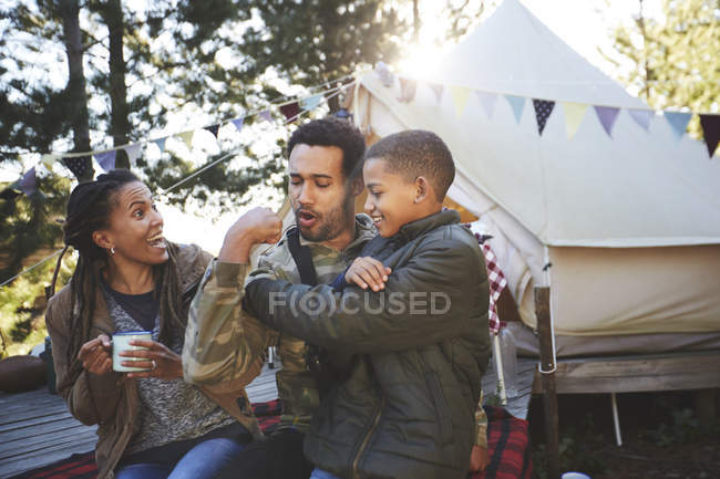 Playful father flexing biceps muscles for son at campsite — Stock Photo