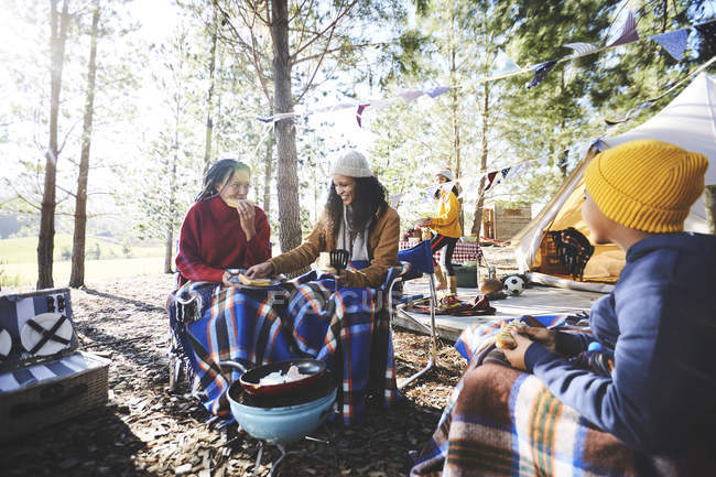 Lesbisches Paar und Kinder essen auf sonnigem Campingplatz — Stockfoto