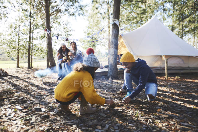 Brother and sister gathering kindling at sunny campsite in woods — Stock Photo