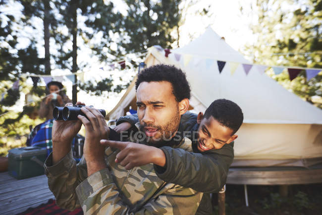 Curioso padre e figlio con binocolo al campeggio — Foto stock