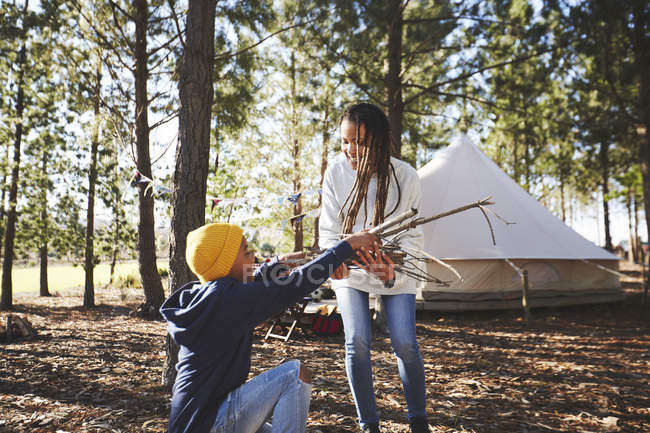 Mère et fils ramassant du bois de chauffage allumant au camping dans les bois — Photo de stock