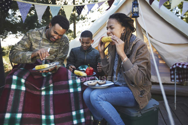 Family eating corn on the cobs at campsite — Stock Photo